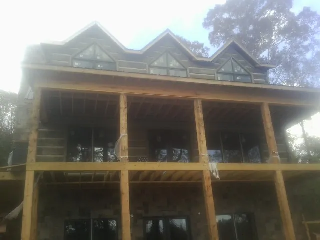 Dormers and porch framing on a large log home under construction — Roof Coating work by our crew in Freeland