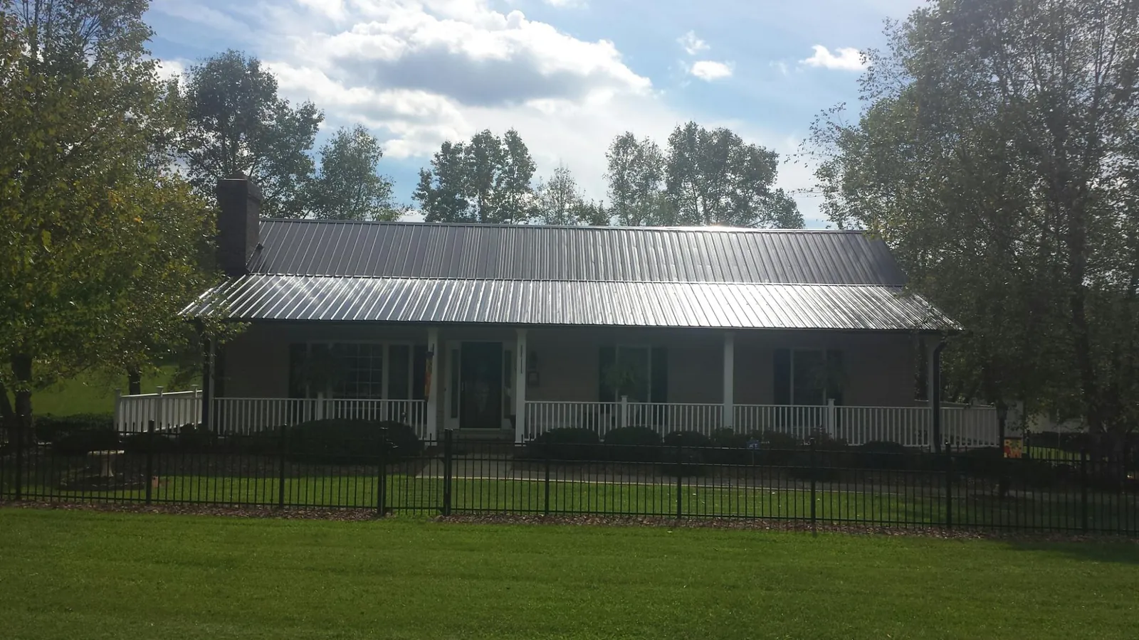 Gray metal roof on a brick ranch with a full width front porch — Gutter Guard Installation work by our crew in Freeland