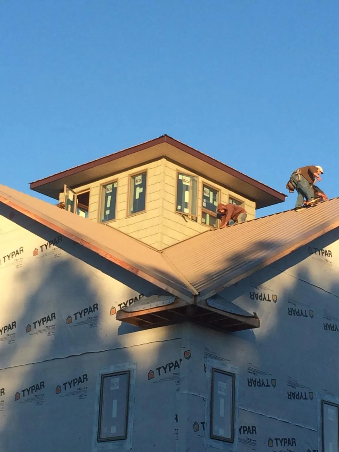 Roofers working around a rooftop cupola on a new metal roof at sunset — Roof Waterproofing in Freeland by Roofing Brothers